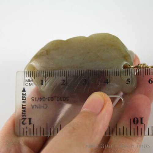Jade carving held lengthwise beside a metric ruler.