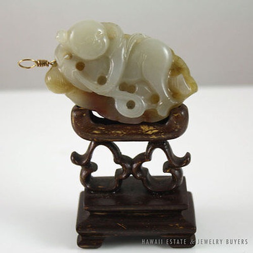 Carved jade figure displayed on its wooden stand.