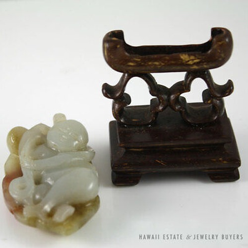 Jade pendant laid beside its upright wooden stand.