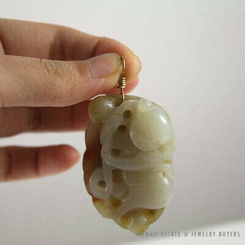 Carved jade pendant held by its suspension loop.