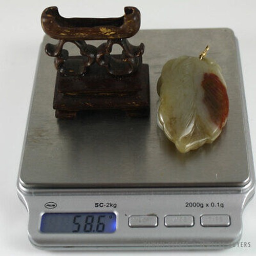 Jade pendant and wooden stand together on a digital scale.