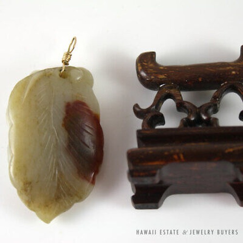 Reverse of the jade pendant showing a russet patch beside the wooden stand.