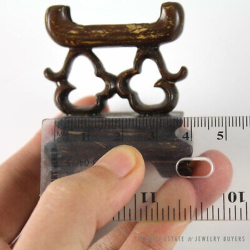 Wooden stand held beside a horizontal ruler.