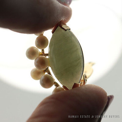 Jade earring held against the light to show the stone's reverse.