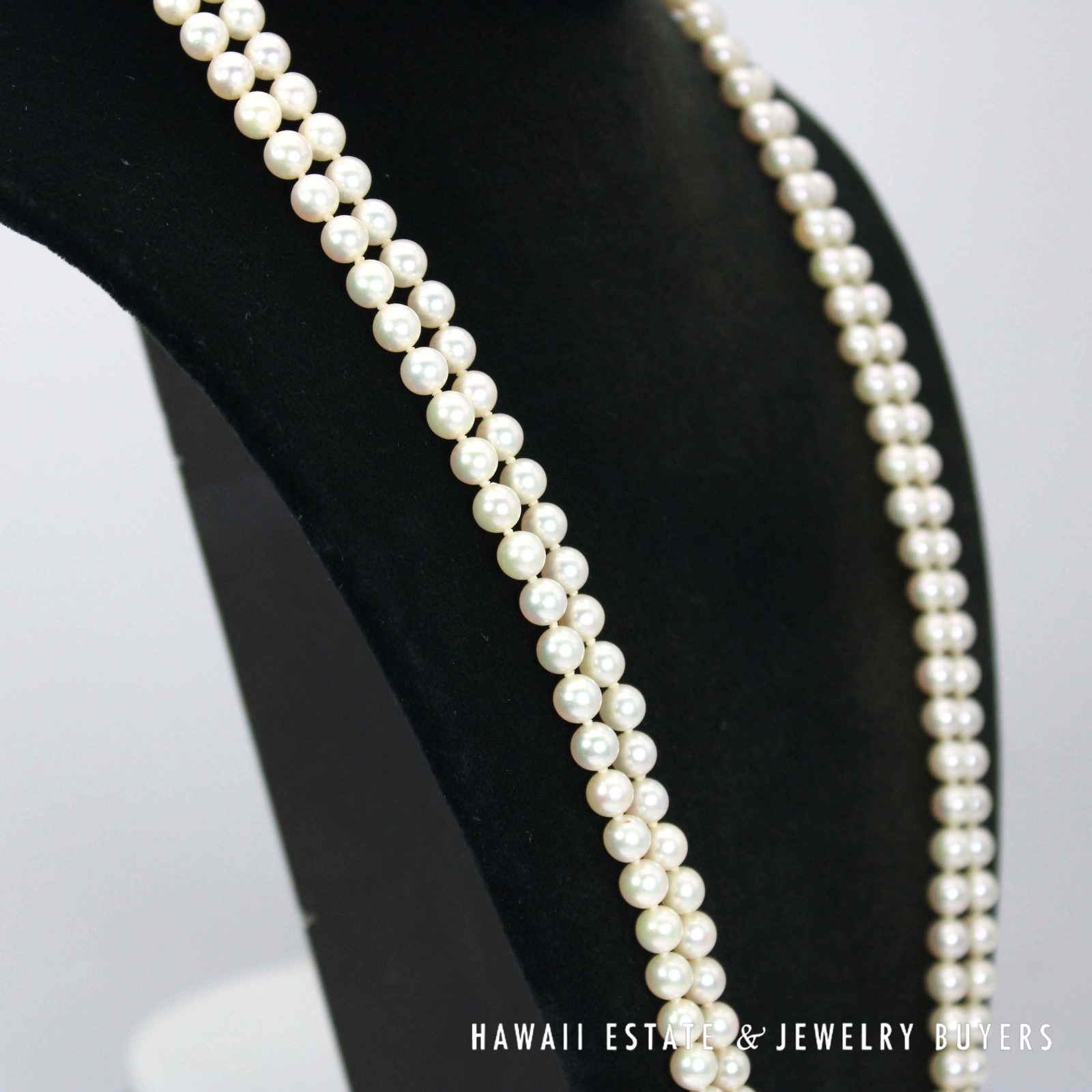 Angled view of the two pearl strands on a black display.