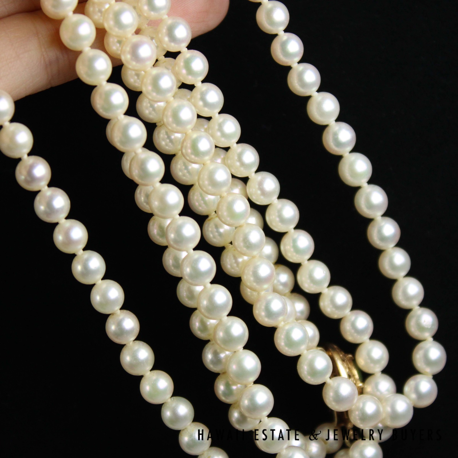 Pearl strands gathered in a hand to show their surfaces and spacing.