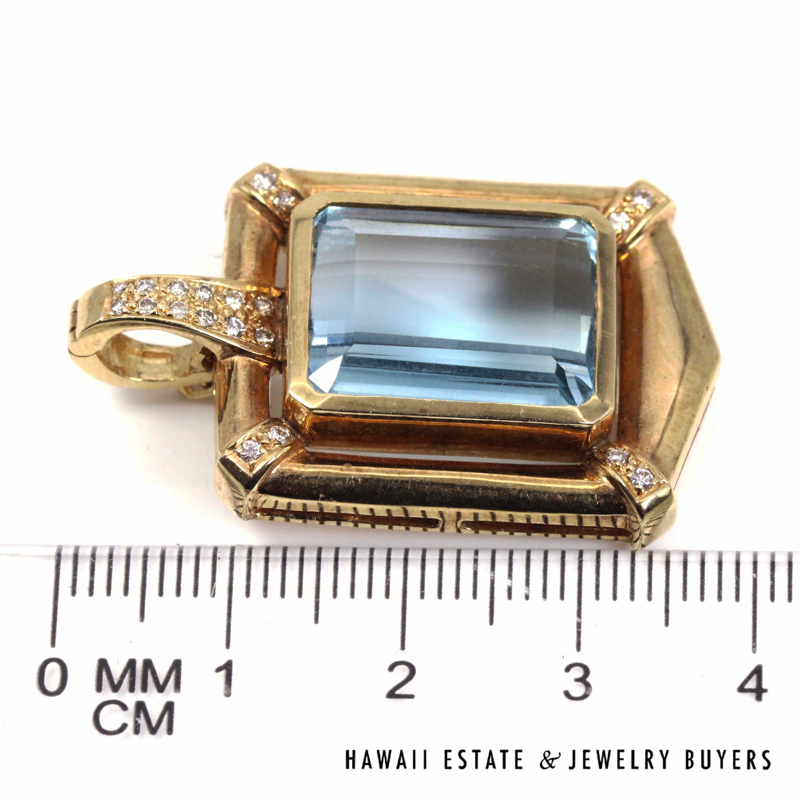 Pendant laid sideways beside a ruler to show its overall height.