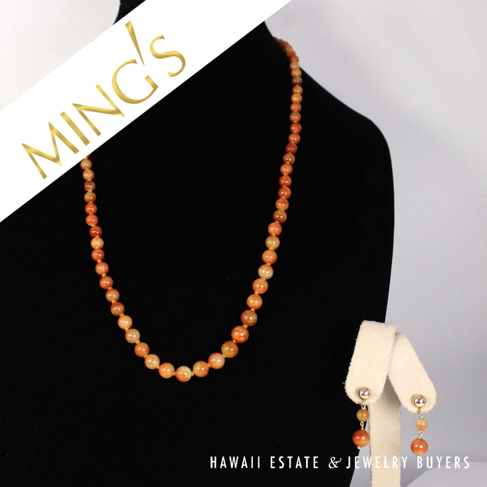 Ming's red-orange jade bead necklace displayed with its accompanying drop earrings.