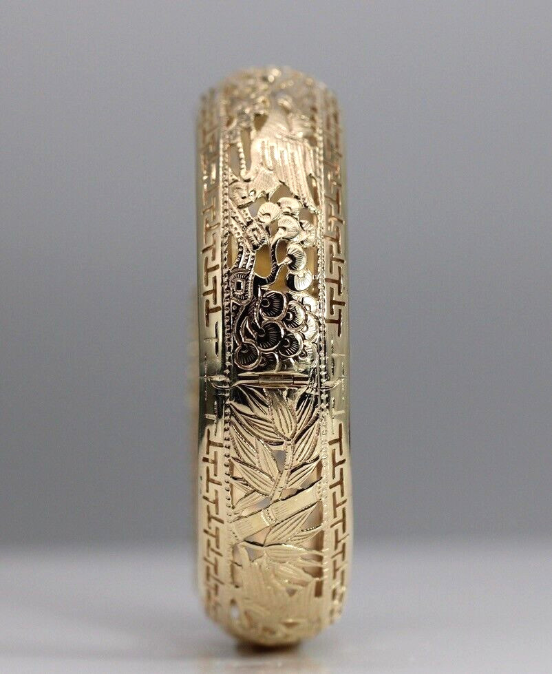 Narrow side view of the bangle showing the hinge, openwork foliage and geometric borders.