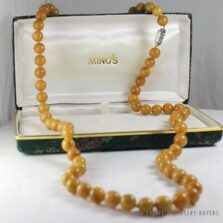 Ming's jade bead necklace draped over an open box, with its white gold clasp visible.