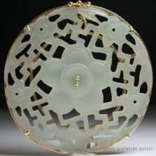 Round Ming's jade pendant with a central carved flower, smaller blossoms and pierced geometric details.