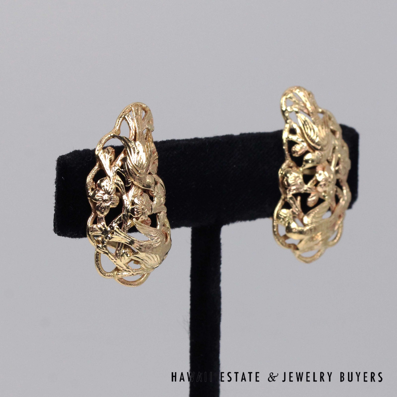 Angled view of the Bird in Plum earrings showing raised birds and blossoms within curved borders.