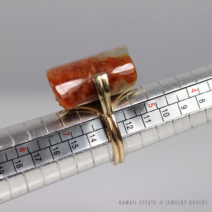 Side view of the ring on a sizing mandrel, showing the gold supports beneath its stone.