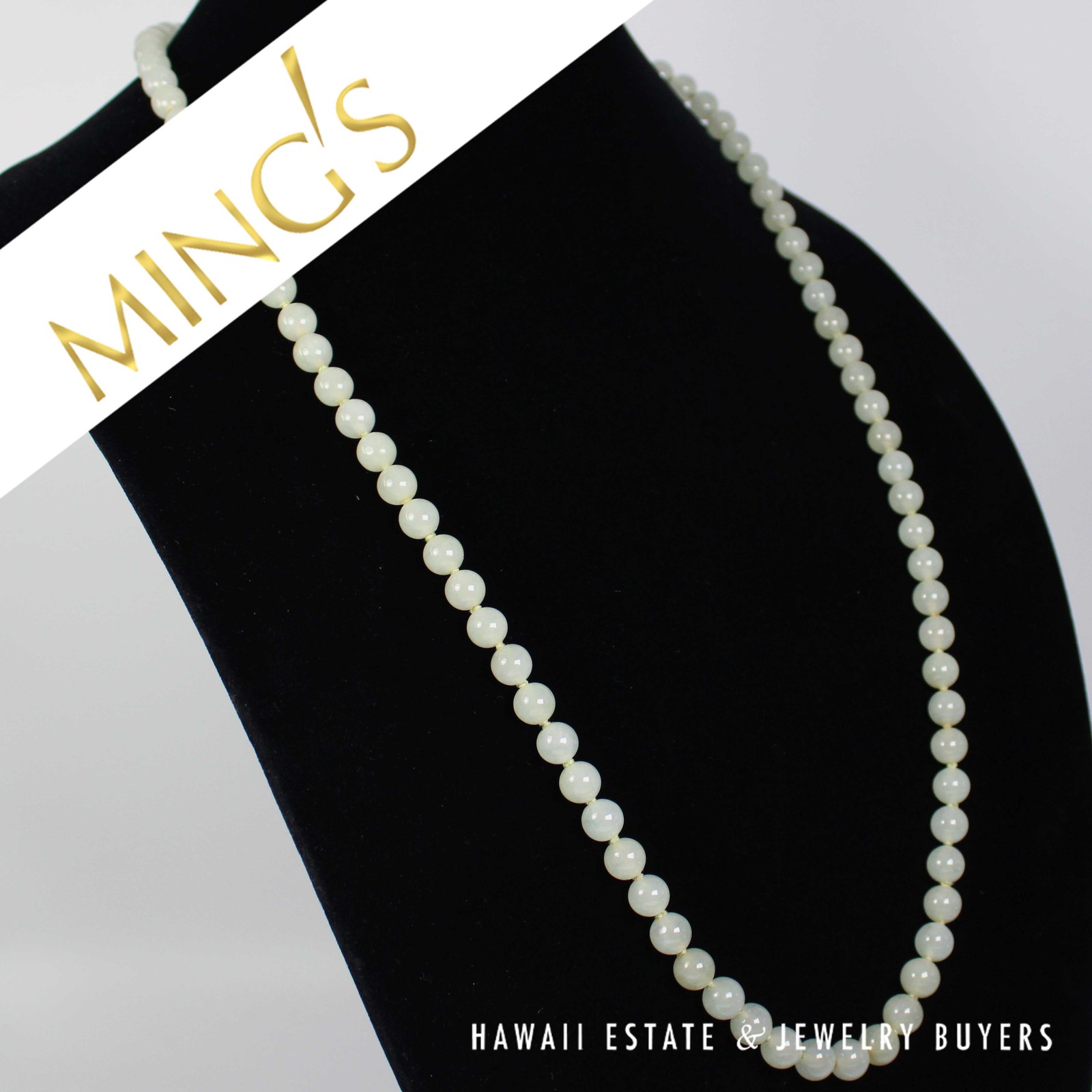 Angled view of the pale green jade necklace on a black bust.