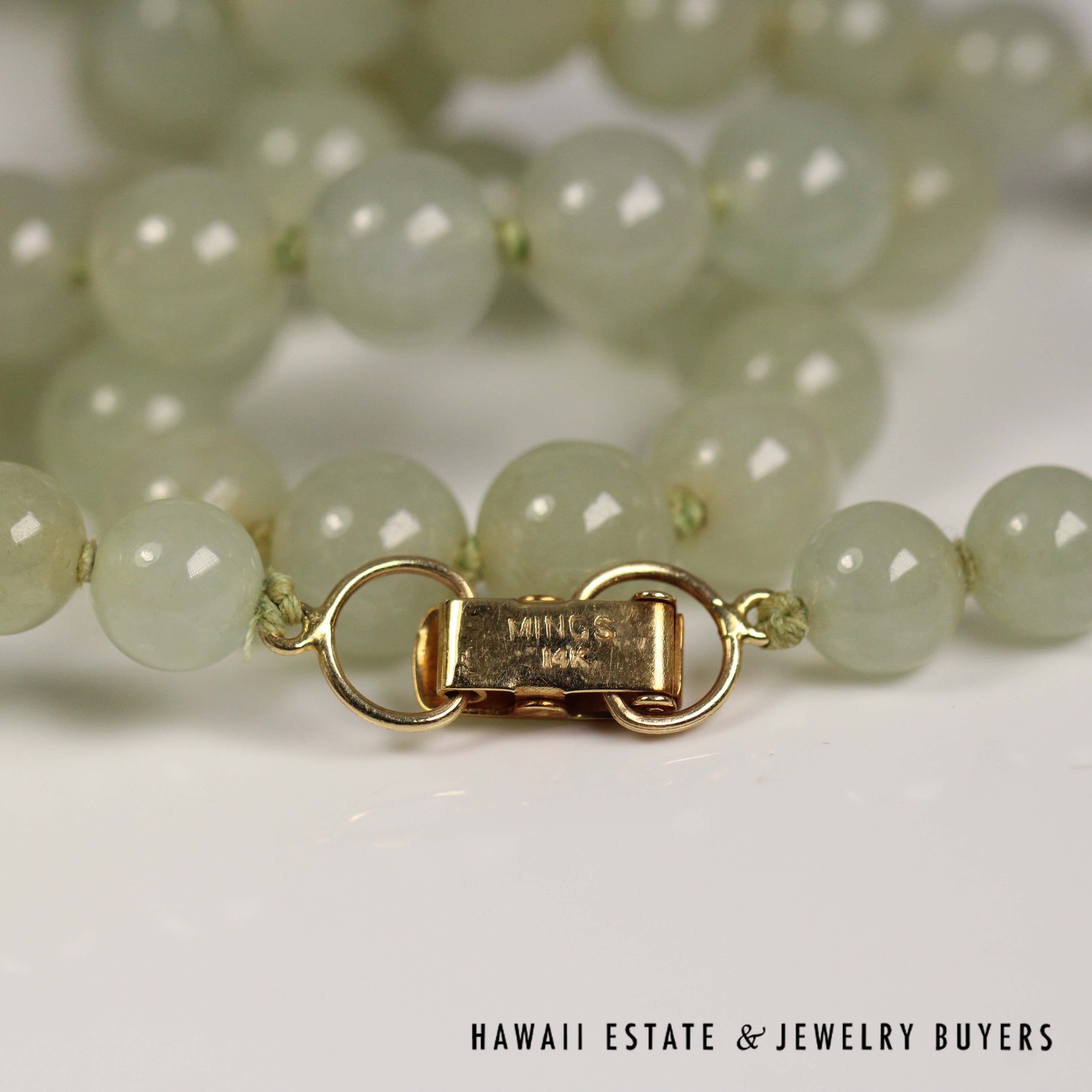 Close-up of stamped markings on the jade necklace's gold clasp.