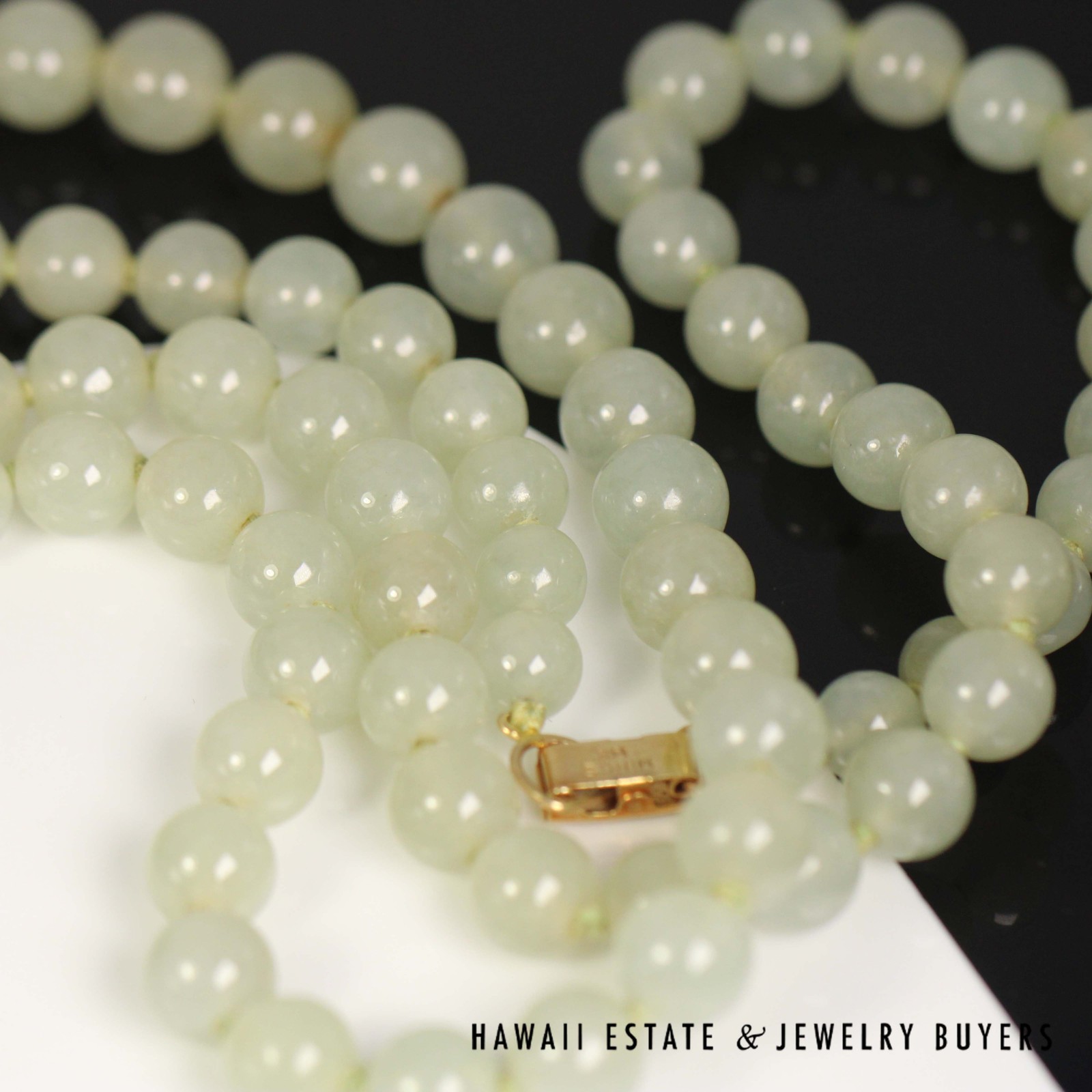 Jade necklace gathered around its yellow gold clasp.