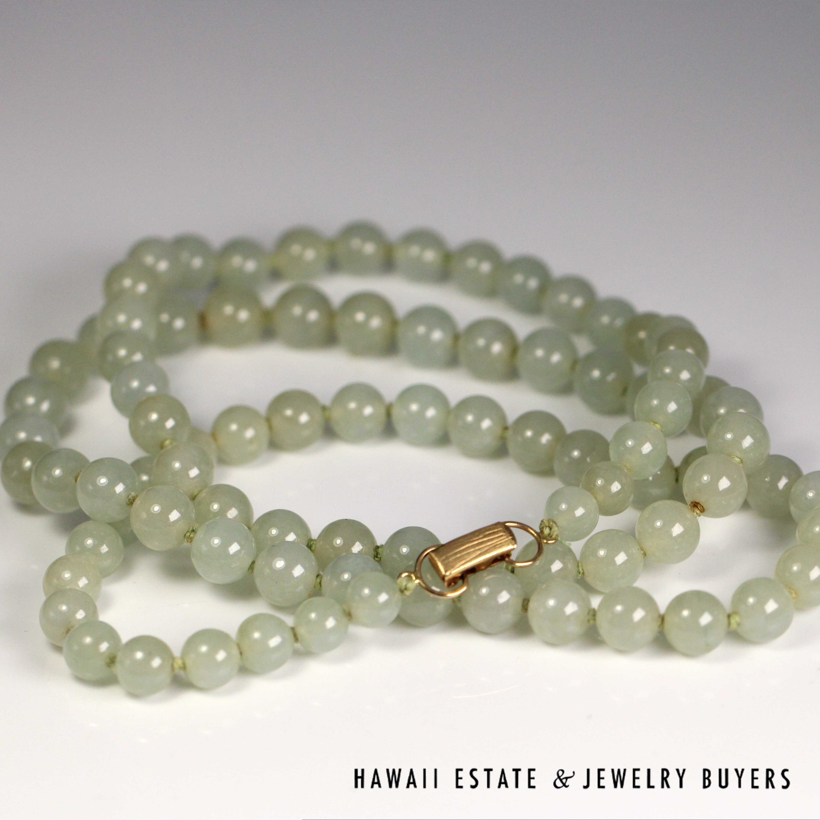 Pale green jade necklace arranged in loops with the clasp facing up.
