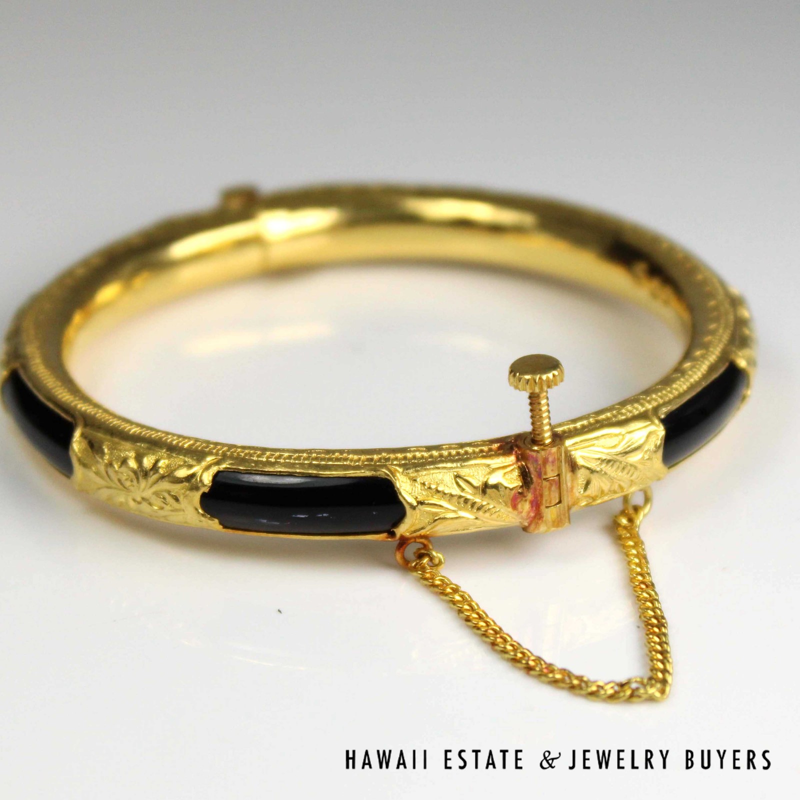 Black plastic bangle with gold sheathing, showing the raised screw closure and attached chain.