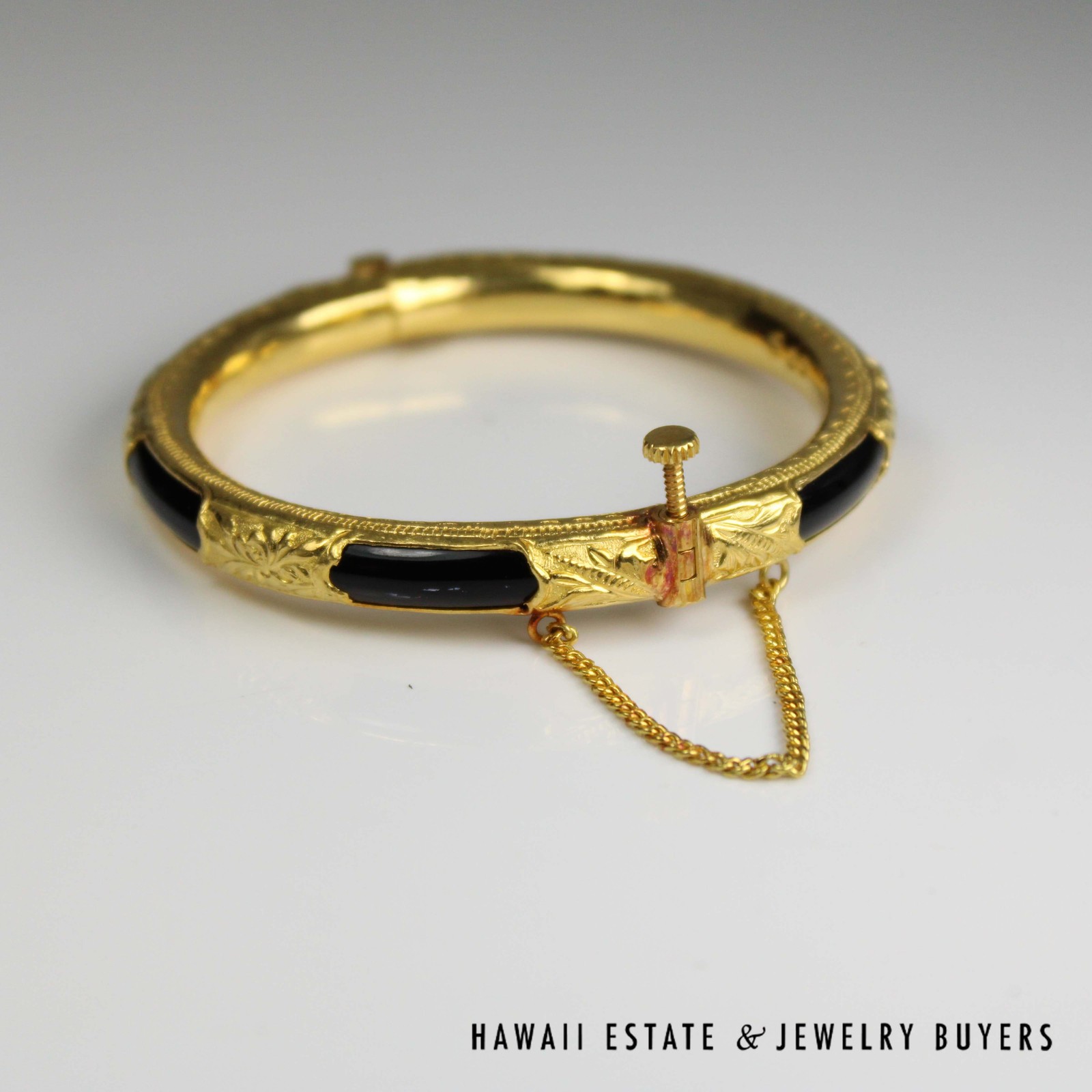Angled view of the black sections, decorated gold sheathing and raised closure screw.